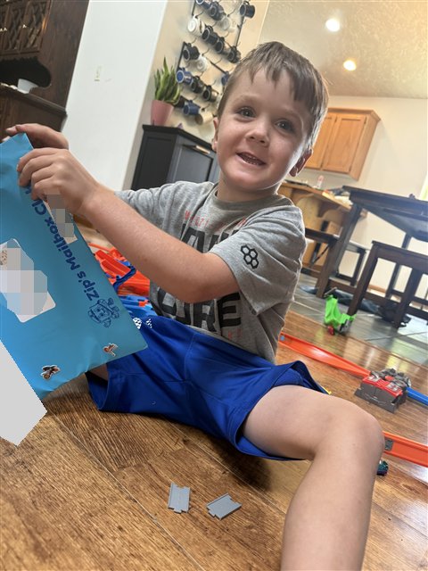 A smiling child opening a blue envelope from Zip