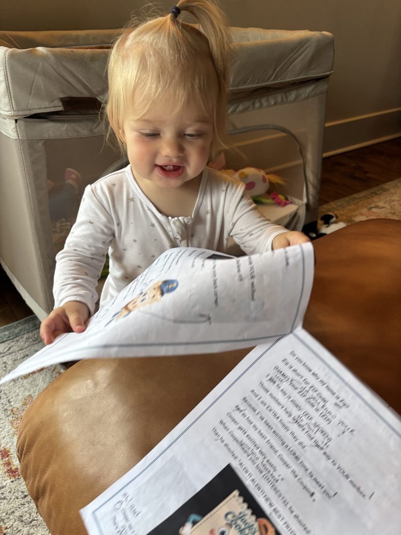 A smiling toddler holding one of Zip's illustrated letters