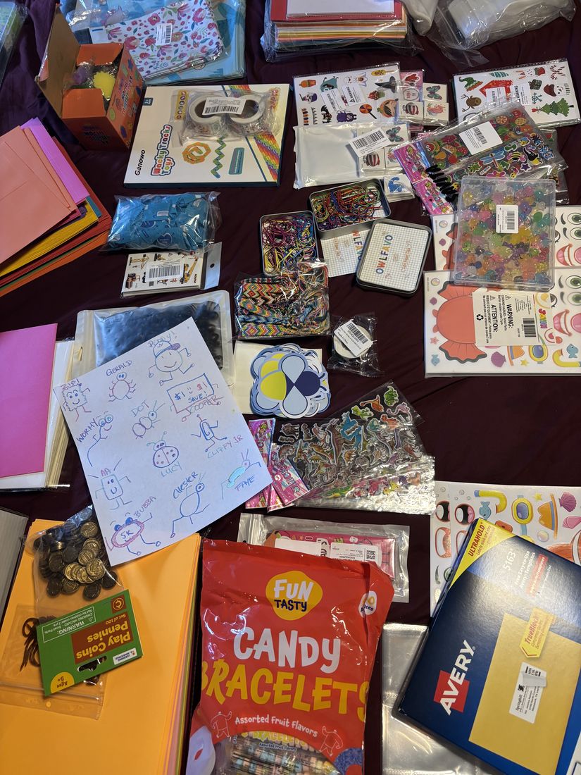 Stickers, activity sheets, little surprises and a child's Crew drawing laid out on the table as a month of Zip's mail is packed by hand