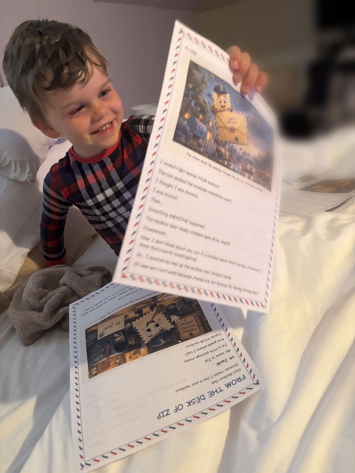 A boy in plaid pajamas grinning as he holds open his personalized letter from Zip