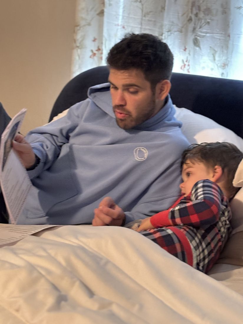 A dad reading a Zip letter aloud with his son snuggled on his lap